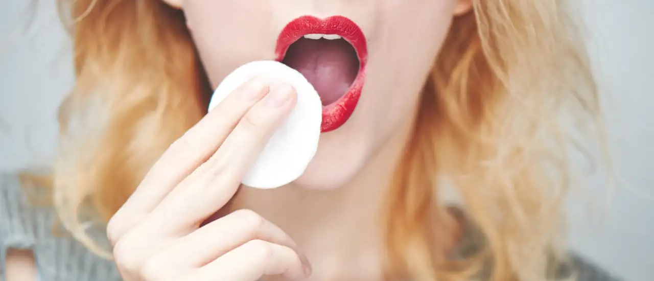 Girl wipes lipstick with a cotton pad