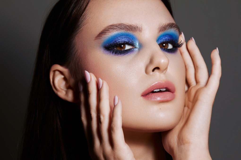 Girl with blue eye shadow touches her face